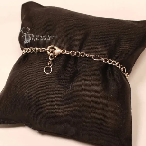 Rückansicht des versilberten Metall-Armbands auf schwarzem Kissen mit Fokus auf den Karabiner-Verschluss.